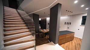 Un intérieur moderne avec un escalier en bois, un coin repas et un banc intégré.