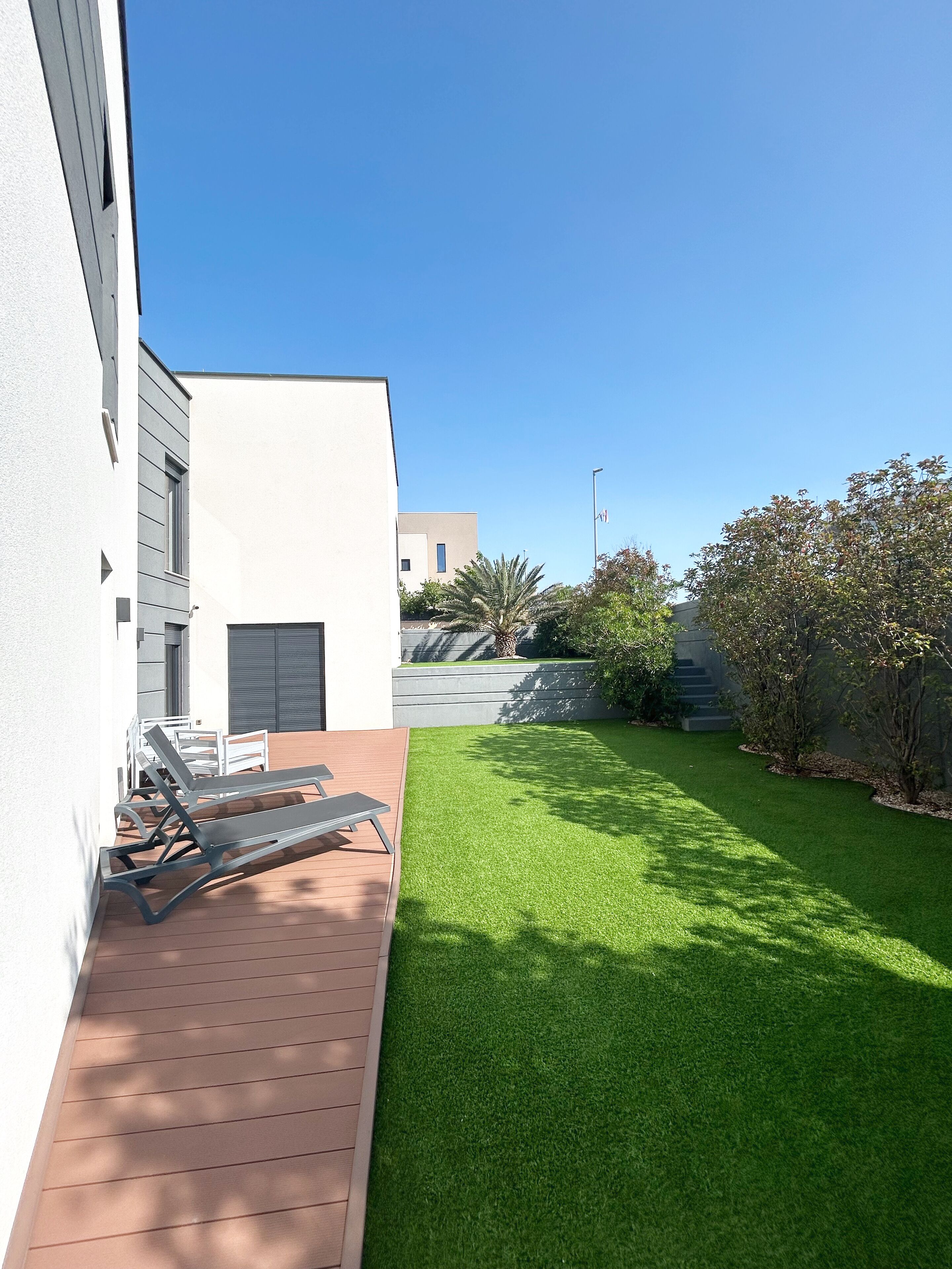 Un edificio moderno con un patio que cuenta con mobiliario exterior y un césped bien cuidado.