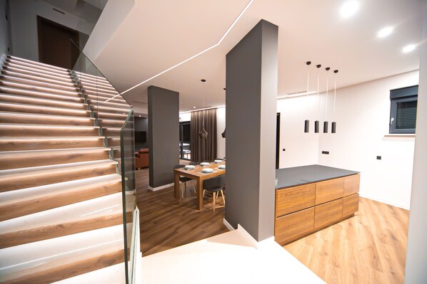 A modern interior with a wooden staircase, a dining area, and a kitchen with a wooden countertop.