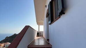 A narrow, tiled corridor with a red-tiled floor leading to a balcony with a view of the sea. - Apartment with sea-view terrace for breathtaking sunsets. (Nebida)