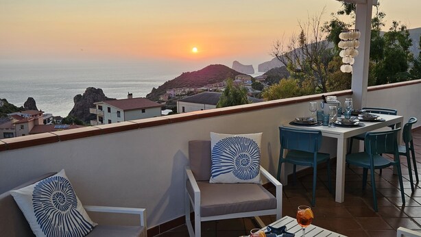A terrace with white furniture, a dining table set for two, and a sunset view over the sea. - Apartment with sea-view terrace for breathtaking sunsets. (Nebida)