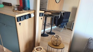 Un espacio habitable compacto con kitchenette, un espejo grande y una pequeña zona de comedor.