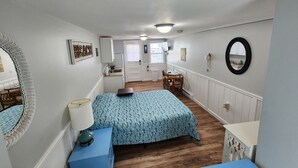 A compact bedroom with a bed, bedside table, lamp, and a small desk.