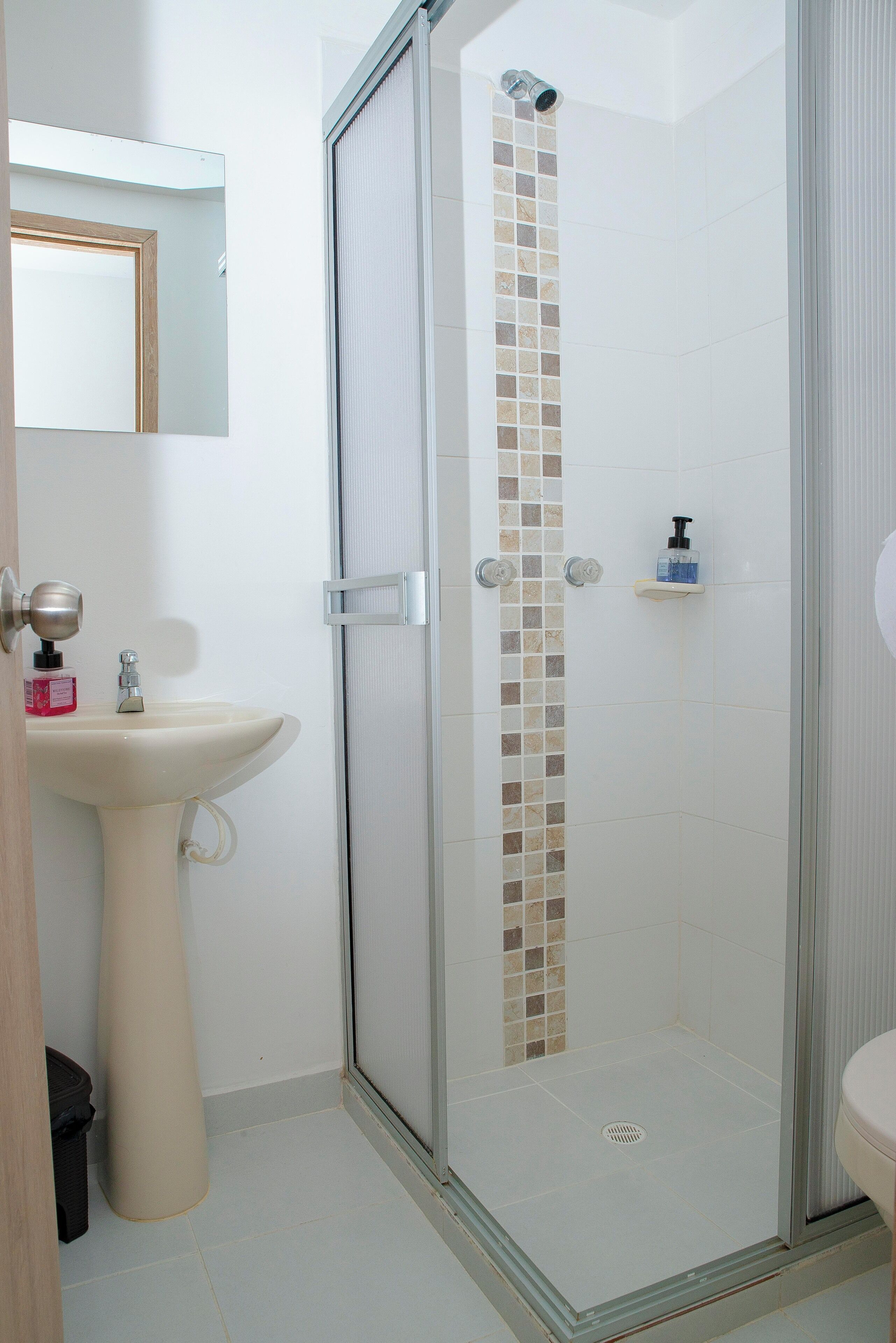 Un baño con ducha de vidrio, lavabo y espejo.