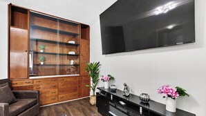 A living room with a large wooden cabinet, a black entertainment center, a flat-screen TV, and a sofa. - Renovo Escape: Game Room + Spa Bath + Views (Renovo)