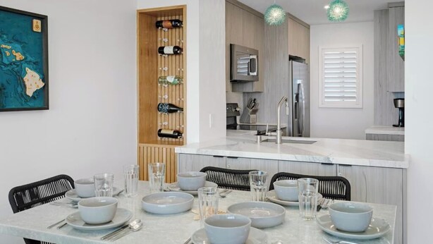 A modern kitchen with a marble countertop, built-in wine rack, and pendant lighting.
