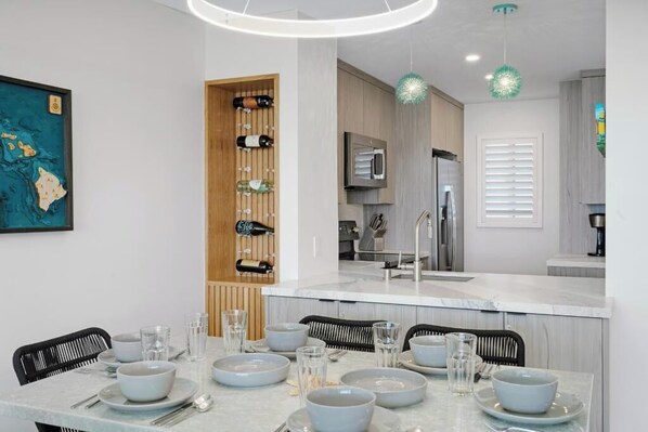A modern kitchen with a marble countertop, built-in wine rack, and pendant lighting.