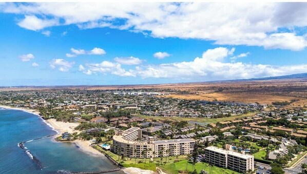 An aerial view of a coastal resort with multiple buildings, a beach, and a clear sky.