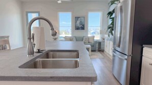 A modern kitchen with a double sink, stainless steel appliances, and a neutral color palette.