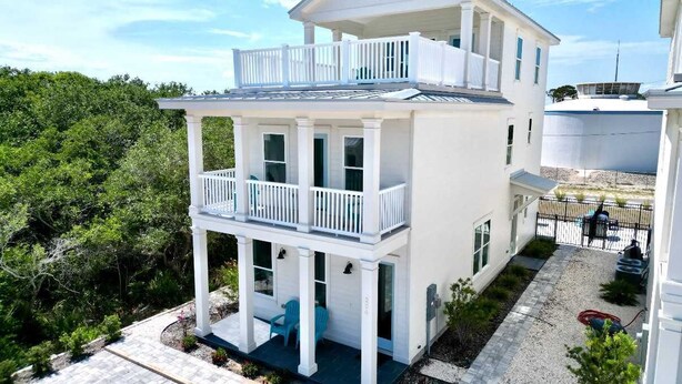 A two-story white house with a balcony, a covered porch, and a small garden area.