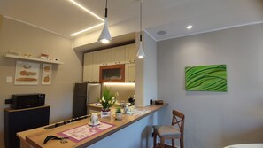 A modern kitchen with a central island, overhead lighting, a refrigerator, and a wall-mounted painting. - EasyDoro Apartment - apartment in the center of Palermo  (Palermo)