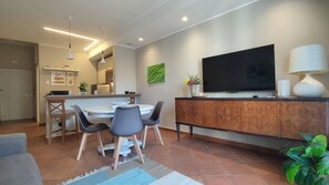 Una sala de estar moderna con comedor, un televisor de pantalla plana y una planta grande en maceta.