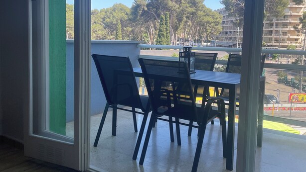 A room with a large sliding glass door leading to an outdoor balcony with a table and chairs. - Apartment in Salou near the beach 10 min drive from Portaventura (Salou)