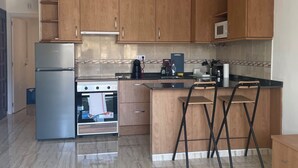 A modern kitchen with wooden cabinets, stainless steel appliances, and a tiled backsplash. - Apartment in Salou near the beach 10 min drive from Portaventura (Salou)