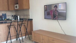 A modern kitchen with wooden cabinets, a microwave, and a dining area with a bench and chairs. - Apartment in Salou near the beach 10 min drive from Portaventura (Salou)