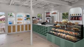 A cafe with a counter, shelves with various items, and a display case with pastries.