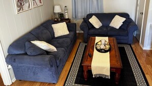 A living room with two dark blue sofas, a wooden coffee table with a tray of snacks, a lamp, and a 'Welcome' sign on the wall. - 2B/2B COZY BEACH GETAWAY IN OCEAN LAKES RESORT MYRTLE BEACH SC w/GOLF CART (Myrtle Beach)