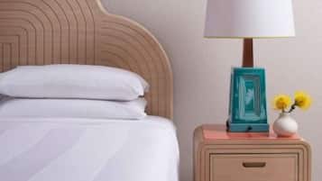 A bedroom with a wooden headboard, a white bed, a nightstand with a lamp, and decorative wall art.