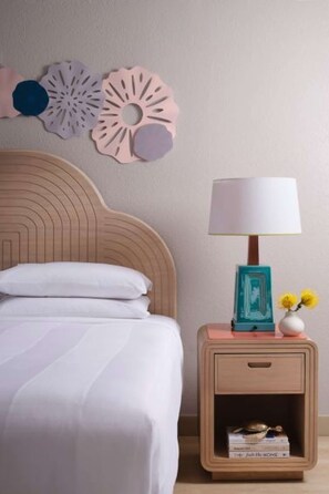 A bedroom with a wooden headboard, a white bed, a nightstand with a lamp, and decorative wall art. - Luxe King Room w/ Balcony | Marina, Golf & Bar (Stuart)