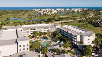 A resort with multiple buildings, a pool area, and a golf course in the background.