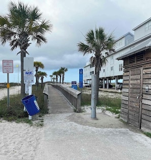 A beachside walkway leading to a building with a beach access sign. - Gulf Shores West Beach Condo/3-Min Walk to Beach/Gulf Views/King Bed (Gulf Shores)