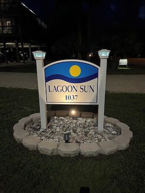 A sign for 'Lagoon Sun 1037' with a sun graphic, surrounded by a concrete planter with rocks.