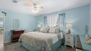 A bedroom with a bed, nightstands, a dresser, a ceiling fan, and a window with curtains. - Gulf Shores West Beach Condo/3-Min Walk to Beach/Gulf Views/King Bed (Gulf Shores)