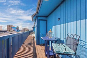 A balcony with a blue railing, a table with a chair, and a lantern.
