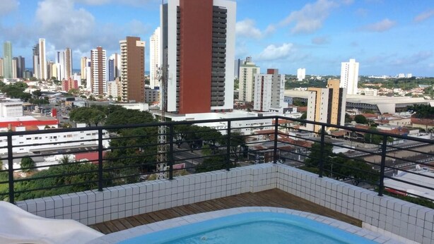 A rooftop pool with a cityscape view, surrounded by a metal railing and white tiled floor. - Apartment in João Pessoa (Pedro Gondim João Pessoa)