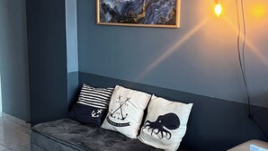 A modern room with a grey sofa, three decorative pillows with nautical designs, and a framed abstract painting on the wall. - Apartment in João Pessoa (Pedro Gondim João Pessoa)