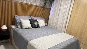 A neatly made bed with a grey duvet, a white throw, and a black pillow with a compass design. - Apartment in João Pessoa (Pedro Gondim João Pessoa)