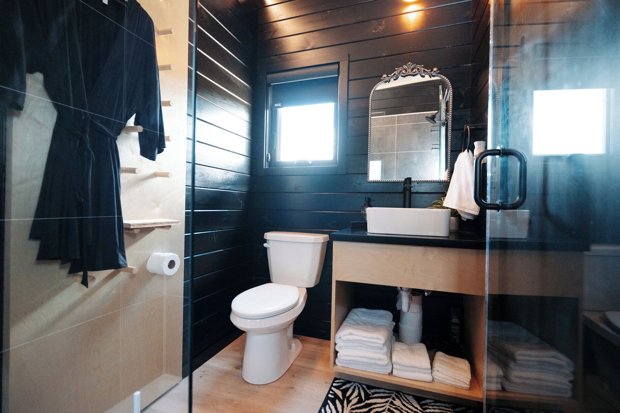 Une salle de bain comprenant des toilettes, un lavabo, un miroir et un porte-serviettes.