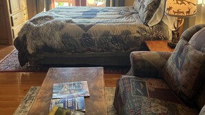 A bedroom with a large bed, a wooden nightstand, a sofa, and a coffee table with books.