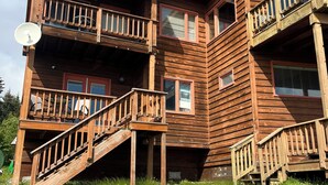 A multi-story wooden building with balconies, a satellite dish, and a chimney.