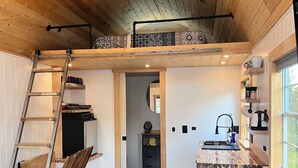 Een compacte, moderne keuken met houten vloeren, een ingebouwde bank en een vide met vloerkleden met prints.