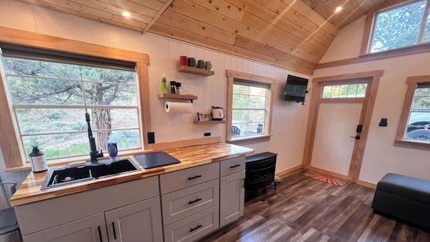 Een moderne keuken met houten kastjes, een houten aanrechtblad en een groot raam dat natuurlijk licht binnenlaat.