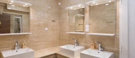 A modern bathroom with two sinks, a shower, and mirrors above each sink.