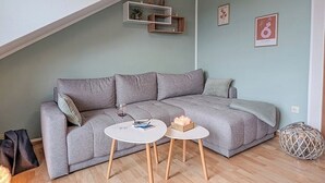A living room with a grey sofa, two small white tables, and a wooden floor. - Refugium Möhneseeblick. our cozy vacation apartment.central and yet quiet. (Möhnesee)