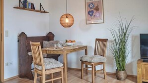 A dining area with a wooden table, two chairs, a hanging light fixture, a bookshelf, and a potted plant. - Refugium Möhneseeblick. our cozy vacation apartment.central and yet quiet. (Möhnesee)