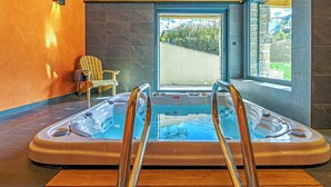 A hot tub with wooden steps, a chair, and a view of a hillside. - CHALET MAÉ (Risoul)