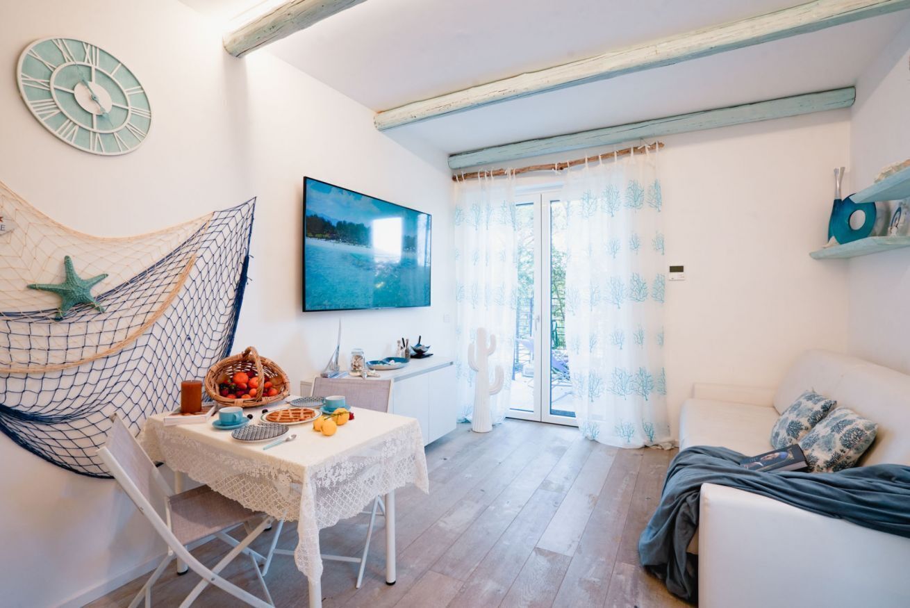 A cozy room with a hammock, a table with fruits and a basket, a TV, and a white sofa.