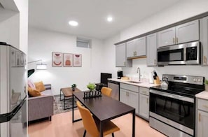 Une cuisine moderne avec des meubles gris, un four en acier inoxydable et un four à micro-ondes. On y trouve également un coin repas avec une table et des chaises.