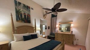 Une chambre à coucher avec un lit à baldaquin, un ventilateur de plafond, une commode et un tableau accroché au mur.