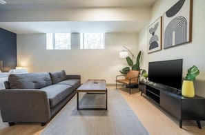 A modern living room with a sofa, coffee table, TV, and artwork on the wall.