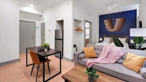 Ein modernes Wohnzimmer mit einer Couch, einem Esstisch mit Stühlen, einer kleinen Pflanze und einem an der Wand hängenden Kunstwerk.