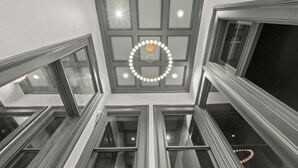 Un intérieur à plusieurs niveaux, doté d’une verrière centrale, de nombreuses fenêtres et d’un luminaire circulaire.