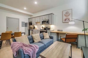 A modern living room with a sofa, coffee table, and a dining area with chairs.