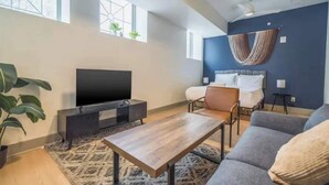 Un salon moderne avec un téléviseur à écran plat, un canapé, une table basse et un lit doté de rideaux.