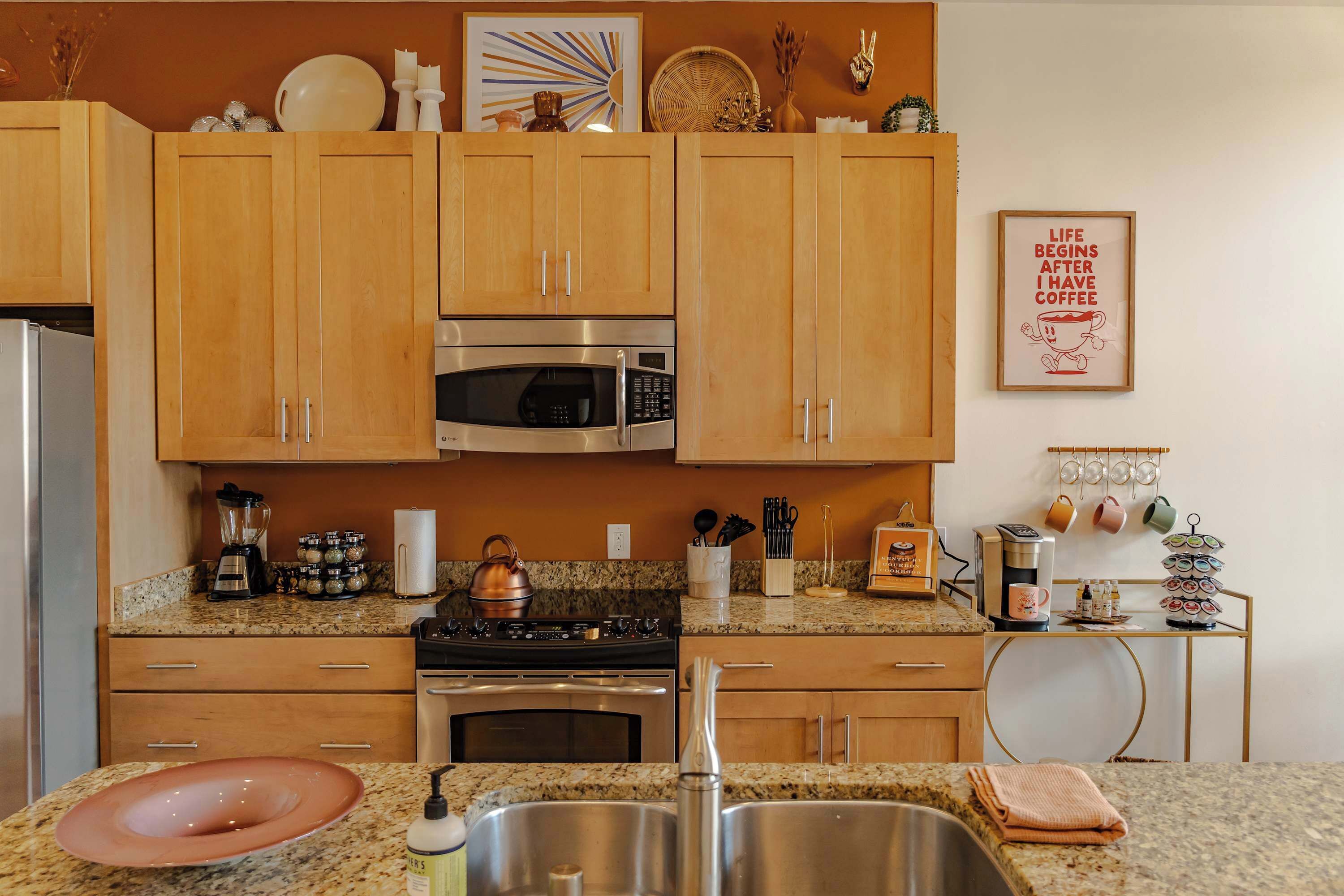 A kitchen with wooden cabinets, stainless steel appliances, granite countertops, and various kitchen items.
