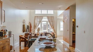 Una cocina moderna con una isla central, armarios de madera y un comedor con una silla y una mesa.